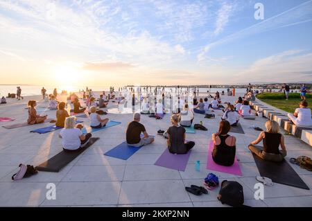 Die Menschen üben Yoga, während die Sonne untergeht am Gruß zur Sonne Monument im Rahmen der Feier des Inernational Yoga Day in Zadar, Kroatien am 17. Juni 2021. Das Denkmal wurde vom kroatischen Architekten Nikola Basic entworfen und symbolisiert die Kommunikation mit der Natur und kommuniziert mit Licht. Foto: Dino Stanin/PIXSELL Stockfoto