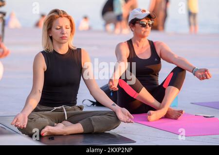 Die Menschen üben Yoga, während die Sonne untergeht am Gruß zur Sonne Monument im Rahmen der Feier des Inernational Yoga Day in Zadar, Kroatien am 17. Juni 2021. Das Denkmal wurde vom kroatischen Architekten Nikola Basic entworfen und symbolisiert die Kommunikation mit der Natur und kommuniziert mit Licht. Foto: Dino Stanin/PIXSELL Stockfoto