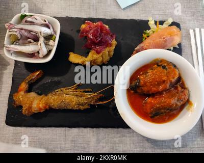 Köstliche Tabletts mit orientalischen Speisen mit Sushi, Garnelen und verschiedenen frittierten Speisen zum Abendessen oder Mittagessen Stockfoto