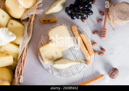 Verschiedene leckere Käse in verschiedenen Arten und Größen auf dem Tisch. Käseköpfe und Stücke auf einem Holzbrett. Frische Milchprodukte, gesunde Bio-Lebensmittel. Entf Stockfoto