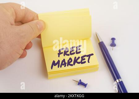 Geschäfts- und Finanzkonzept. Der Mann blättert durch die Aufkleber, auf dem Blatt steht "FREIER MARKT" Stockfoto