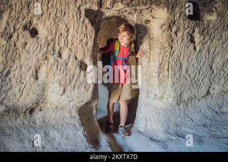 Junge Touristen, die das Tal mit Felsformationen und Feenhöhlen in der Nähe von Goreme in Kappadokien, Türkei, erkunden Stockfoto
