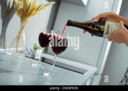 Die Hand einer Frau gießt zu Hause Rotwein in Gläser mit Eis Stockfoto