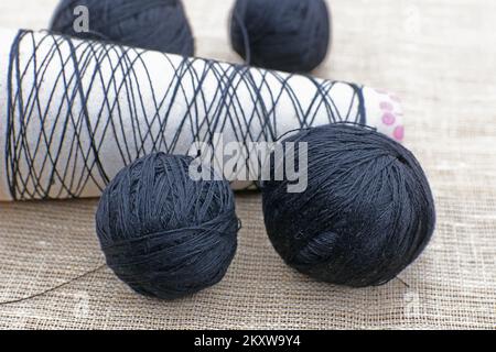 Gewindekugeln zum Stricken und eine leere Gewindespule. Stockfoto