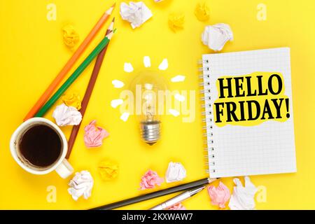 Geschäfts- und Bildungskonzept. Auf gelbem Hintergrund eine Tasse Kaffee, eine Glühbirne, Bleistifte, ein Notizbuch mit der Aufschrift "HALLO FREITAG" Stockfoto