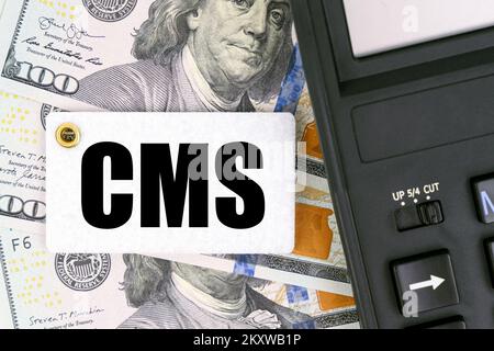 Geschäfts- und Finanzkonzept. Auf der Tabelle befinden sich Dollars, ein Taschenrechner und ein Tag mit der Aufschrift CMS Stockfoto