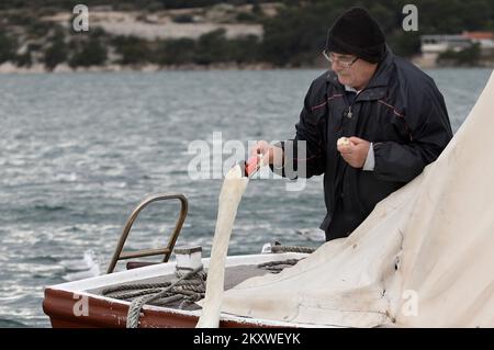 Ein Fischer füttert am 5. Dezember 2021 einen Schwan von seinem Boot in Sibenik, Kroatien. Ein Schwan verlor seine Freundin vor 6 Jahren und fand einen Freund im Fischer, der ihm keinen Namen geben will, weil der Schwan kommt, um sein Essen abzuholen und sich zu unterhalten, sobald er das Boot hört. Foto: Dusko Jaramaz/PIXSELL Stockfoto