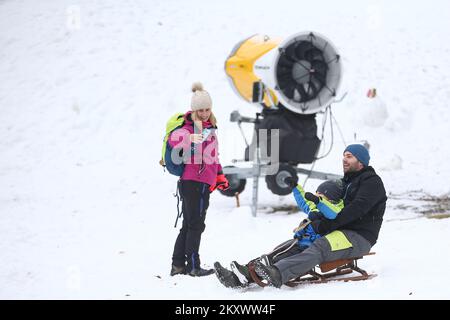 Vater und Kind genießen Schlittenfahrten auf Sljeme, dem Gipfel von Medvednica, in Zagreb, Kroatien, am 27. Dezember 2021. Foto: Matija Habljak/PIXSELL Stockfoto