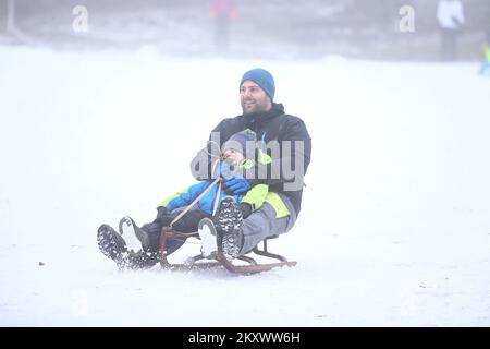 Vater und Kind genießen Schlittenfahrten auf Sljeme, dem Gipfel von Medvednica, in Zagreb, Kroatien, am 27. Dezember 2021. Foto: Matija Habljak/PIXSELL Stockfoto