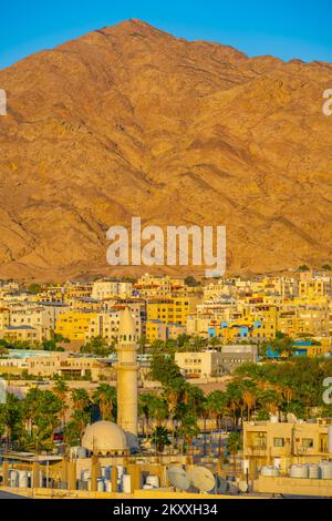 Blick über die Dächer von Aqaba in Jordanien bis zu den Hügeln hinter den Kulissen bei Sonnenuntergang Looking über die Dächer von Aqaba in Jordanien Stockfoto