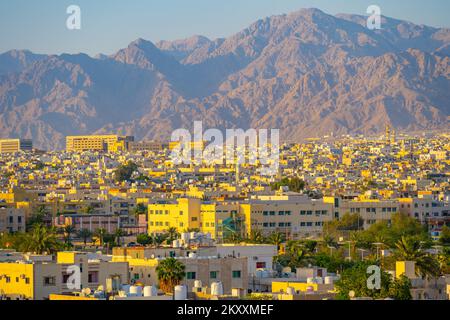 Blick über die Dächer von Akaba in Jordanien bis zu den Hügeln hinter dem Hotel bei Sonnenuntergang Stockfoto