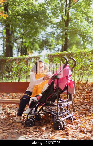 Ältere Frau mit Kinderwagen im Park, die sich um ihre Enkelin kümmert. Platz für Text. Stockfoto