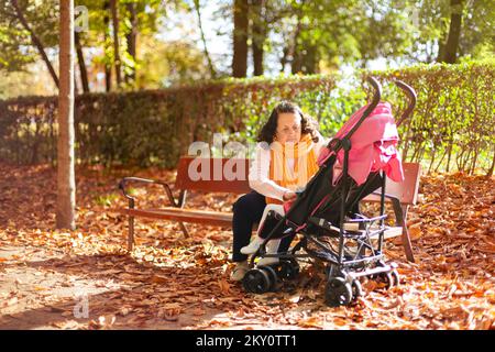 Großmutter mit Kinderwagen kümmert sich um ihre Enkelin im Park. Platz für Text. Stockfoto