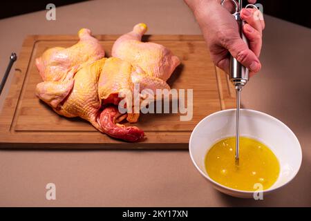 Der Küchenchef bereitet rohes Hähnchen in der Küche zu. Der Mensch bereitet rohes Hähnchen zum Grillen zu und injiziert dabei Cider in das Fleisch. Nahaufnahme. Stockfoto