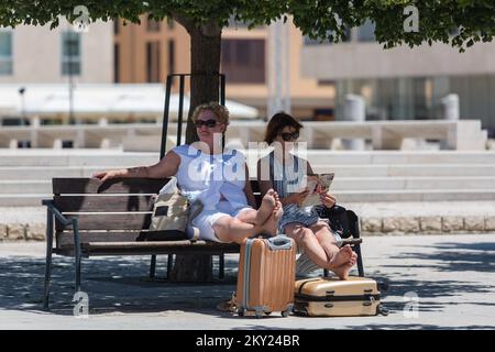 Weibliche Touristen mit Koffern ruhen am 2. Juli 2022 auf einer Bank in Zadar, Kroatien. Im Vergleich zu 2019 im Juni verzeichnete die Stadt Zadar TZ einen Anstieg der Anzahl der Übernachtungen um 2 Prozent, und 87 Prozent der Ankünfte aus dem Rekordjahr 2019 wurden erreicht. Foto: Sime Zelic/PIXSELL Stockfoto