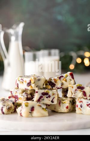 Weiße Schokolade, Cranberry und Pistazien-Fudge serviert mit Milch. Stockfoto