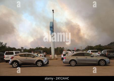 Die Leute parkten ihre Autos in der Nähe des Zaton-Geländes im Hinterland von Vodice, wo die Straße aufgrund eines großen Feuers gesperrt ist, Kroatien am 13. Juli 2022. Etwa 30 Feuerwehrleute mit einem Dutzend Fahrzeugen sind am Boden, und zwei Canadairs haben das Feuer gemeinsam mit den Bodentruppen gelöscht. Es gibt Kiefernwälder oben, niedrige Vegetation und gefährdete Gebäude. Foto: Dusko Jaramaz/PIXSELL Stockfoto