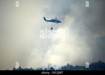 Feuerwehrleute versuchen mit einem Hubschrauber, ein Waldfeuer im Dorf Temnica in Slowenien, 22. Juli 2022 zu löschen. Rund 1.000 Feuerwehrleute haben im Westen Sloweniens einen großen Waldbrand bekämpft. Das Feuer, das durch den Wind aus Ostitalien geblasen wurde, führte zur Evakuierung mehrerer Dörfer. Foto: Sasa Miljevic/PIXSELL Stockfoto