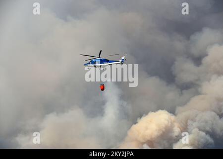 Feuerwehrleute versuchen mit einem Hubschrauber, ein Waldfeuer im Dorf Temnica in Slowenien, 22. Juli 2022 zu löschen. Rund 1.000 Feuerwehrleute haben im Westen Sloweniens einen großen Waldbrand bekämpft. Das Feuer, das durch den Wind aus Ostitalien geblasen wurde, führte zur Evakuierung mehrerer Dörfer. Foto: Sasa Miljevic/PIXSELL Stockfoto