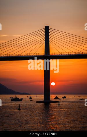 Die Sonne untergeht über der Peljesac-Brücke während der Eröffnungsfeier der Peljesac-Brücke am 26. Juli 2022 in Komarna, Kroatien. Foto: Zvonimir Barisin/PIXSELL Stockfoto