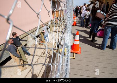 Point Pleasant, N.J., 4. April 2013 Ein Bauteam arbeitet an Pfählen für einen Abschnitt der Promenade, während sich die Schüler für einen Besuch im Jenkinson's Aquarium anstellen. Nach dem Hurrikan Sandy gibt es zwar noch viel zu tun, aber die Leute kehren bereits zurück, um die Promenade zu genießen. Hurrikan Sandy Aus New Jersey. Fotos zu Katastrophen- und Notfallmanagementprogrammen, Aktivitäten und Beamten Stockfoto