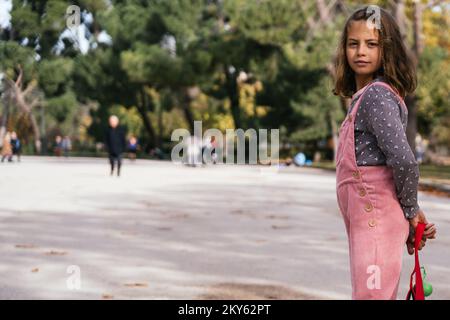 Das hübsche blonde Mädchen in Pink, die Hände hinter dem Rücken, sieht mit Bedacht auf die Kamera und schafft so einen großen Kopierraum Stockfoto