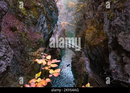 Gorges de l'Areuse, Noiraigue , Neuchatel, Schweiz, Europa. Romantische Steinbrücke über den Fluss mit herbstlicher Jura-Berglandschaft. Stockfoto