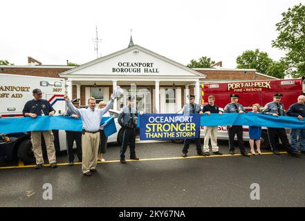 Oceanport, N.J., 24. Mai 2013 Bürgermeister Michael J. Mahon, zusammen mit Polizei, Feuerwehrleuten und Stadtbewohnern, schneidet ein zeremonielles Band. Die Veranstaltung feiert alle Mitarbeiter des Stadtbezirks für ihren Dienst an der Gemeinde nach Hurrikan Sandy. Hurrikan Sandy Aus New Jersey. Fotos zu Katastrophen- und Notfallmanagementprogrammen, Aktivitäten und Beamten Stockfoto