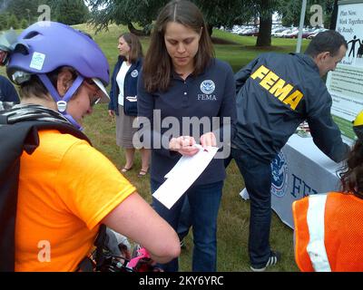 Seattle, Washington, 21. Juni 2013 Ein FEMA-Mitarbeiter teilt Informationen zur Notfallbereitschaft mit einem Radfahrer. Die Veranstaltung, die sogenannten Seattle Disaster Relief Trials, konzentrierte sich darauf, wie Fahrräder für die Notfallvorsorge eingesetzt werden können, um auf potenzielle Katastrophenszenarien zu reagieren. Radfahrer fuhren über einen 10 km langen Kurs mit Kontrollpunkten entlang des Weges, die sich auf Aktivitäten und Herausforderungen zum Aufbau von Fähigkeiten konzentrierten. Dazu gehörten das Sammeln von erste-Hilfe-Materialien und das Erlernen der Grundlagen der ersten Hilfe, das Sammeln und Transportieren von Lebensmitteln, Wasser und Sandsäcken, das Abschließen von Aktivitäten zur Kommunikationsvorbereitung und das Bewegen von Fahrräten und Ausrüstung Stockfoto