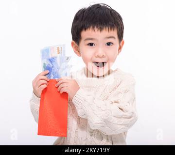 Ein glücklicher asiatischer Junge, der Geld zeigt und einen roten Umschlag in der Hand hat. Frohes Chinesisches Neujahrskonzept. Stockfoto