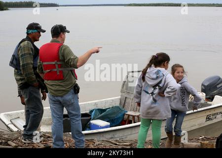 Fort Yukon, Alaska, 6. Juli 2013 die Kinder der amerikanischen Ureinwohner Gadzow sehen zu, wie die FEMA-Inspektoren Schäden aufzeichnen und die Immobilien der Subsistenzfischer Clarence Oldman im Gebiet von North Census inspizieren, nachdem schwere Überschwemmungen ihre Lachsmühlen, Netze und Lebensweise zerstört hatten. Die FEMA befolgt und unterstützt die Richtlinie, dass Bundesbehörden mit Stammesregierungen in einer Beziehung zwischen Regierung und Regierung zusammenarbeiten. Die FEMA unterhält seit langem enge Beziehungen zu Stammesregierungen und sie sind wichtige Mitglieder des Notfallmanagementteams. Fotos zu Katastrophen Stockfoto