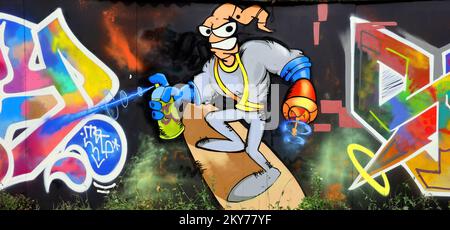 Farbenfroher Hintergrund der Graffiti-Malerei mit hellen Aerosolstreifen an der Metallwand. Alte Straßenkunst aus Spraydosen. Zeitgenössische Jugendkultur im Hintergrund Stockfoto