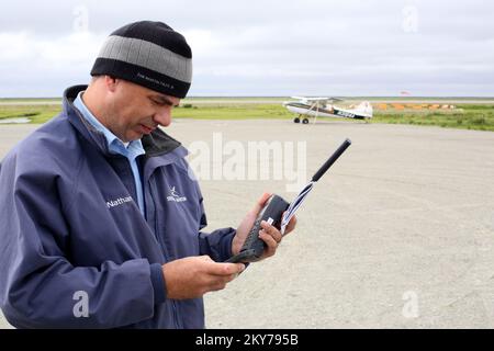 Alakanuk, Alaska, 16. Juli 2013 Security Air Pilot Nathan Semler ruft die Flugkontrolle über Satelitte-Telefon im abgelegenen westlichen Yukon-Gebiet an, um Erlaubnis zu erhalten, von diesem Schotterflugplatz abzuheben. Die FEMA reagiert auf Einladung des Gouverneurs mit Teams, um mit dem Staat Alaska und den Überlebenden der Katastrophe zusammenzuarbeiten. Adam DuBrowa/FEMA. Fotos zu Katastrophen- und Notfallmanagementprogrammen, Aktivitäten und Beamten Stockfoto