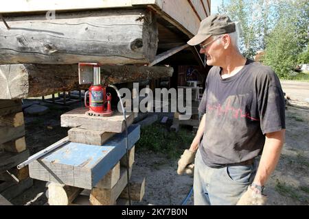 Galena, Alaska, 23. Juli 2013 Nachdem John Stams Haus vor kurzem durch eine Flut verwüstet wurde, hebt er das Gebäude vier Meter über das vorherige Basisniveau, um weitere sich wiederholende Schäden zu begrenzen. Der Hauseigentümer verwendet druckluftgefüllte Heber, um das Haus an jeder Ecke alleine anzuheben, während sein FEMA-Antrag aussteht. Adam DuBrowa/FEMA. Fotos zu Katastrophen- und Notfallmanagementprogrammen, Aktivitäten und Beamten Stockfoto