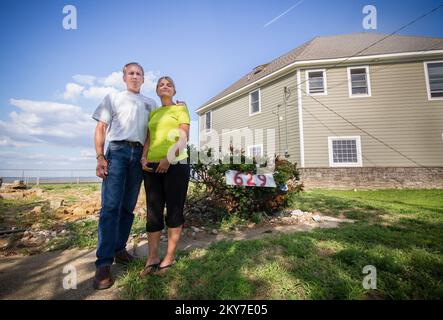 Union Beach, N.J., 30. Juli 2013 die Familie Sochaki steht auf dem leeren Parkplatz, wo ihr Zuhause stand, bevor sie es an Hurrikan Sandys Flutwasser verlor. Die Familie beherbergte sich im Haus ihrer Schwiegermutter, hinter dem Paar. Dieses Haus war mit gegossenen Betonwänden und anderen Verstärkungselementen befestigt, die es möglich machten, dass das Haus aus Sandy fast unversehrt hervorging. Hurrikan Sandy Aus New Jersey. Fotos zu Katastrophen- und Notfallmanagementprogrammen, Aktivitäten und Beamten Stockfoto
