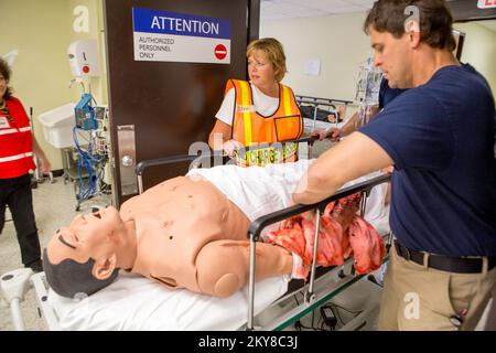 Anniston, Ala., 24. April 2014 Lara Blake, eine Leiterin des Krankenhausbetriebs an der University of Kentucky, übernimmt die Versorgung eines simulierten Patienten mit einer Armamputation während des Integrated Capstone Event (ICE) in der Notaufnahme des Center for Domestic Preparedness in Anniston, Alabama. Etwa 80 medizinische Fachkräfte und Notfallhelfer, die acht der 13 regionalen Koalitionen repräsentieren, die an der Noble Training Facility des CDP und dem Advanced Responder Training Complex ausgebildet wurden. Diese Mitarbeiter aus der Abteilung Healthcare Leadership sind Kollegen aus den USA beigetreten Stockfoto