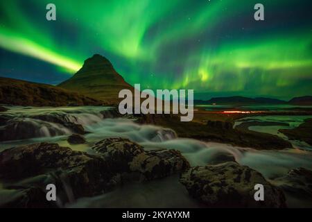 Lebendige Auroras schweben über Kirkjufell, Island, und beleuchten den Himmel und reflektieren die ruhige Landschaft darunter in einer schillernden Darstellung der Natur Stockfoto