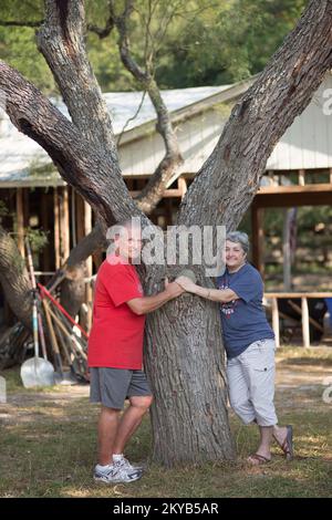 Wimberley, TX, USA 26. August 2015 Bewohner von Wimberley Carmen und Paul Polhemus stehen vor einem Hinterhof, wo sie sich während der Blitzflut vom 23.. Mai auf Ästen ruhten, bevor sie zum Haus ihrer Nachbarn schwimmen. Die Polhemus hatten elf Fuß Wasser in ihrem Haus von der Blitzflut des Blanco Flusses. Andrea. Schwere Stürme, Tornados, Stürme und Überschwemmungen in Texas. Fotos zu Katastrophen- und Notfallmanagementprogrammen, Aktivitäten und Beamten Stockfoto