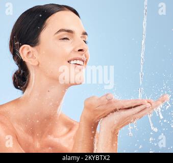 Frau, Hände und Reinigung im Studio für Hautpflege, Wasser und Spritzer vor blauem Hintergrund Modell. Mädchen, entspann dich und Dusche mit Schönheitsspritzer in einem Stockfoto