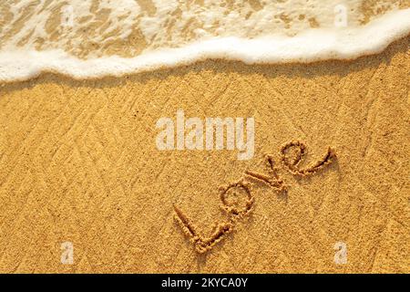 Das Wort Liebe im Sand am Strand geschrieben Stockfoto