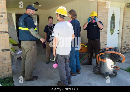 Division K AmeriCorp Freiwillige treffen sich mit dem FEMA Strike Team Leader Sean Smith vor einem durch die Flut beschädigten Haus. Sie sollen New Roads, La., ausradieren. Schwere Stürme und Überschwemmungen in Louisiana. Fotos zu Katastrophen- und Notfallmanagementprogrammen, Aktivitäten und Beamten Stockfoto
