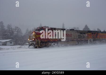 Eine BNSF GE C44-9W dieselelektrische Lokomotive, die einen Güterzug mit Öltankern fährt, die die Gleise in Troy, Montana, entlangfahren. Stockfoto