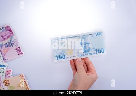 Hand mit Turksh Lira-Banknote auf weißem Hintergrund Stockfoto