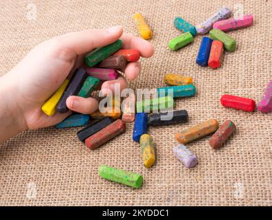 Benutzte Farbstifte und eine Hand, die etwas hielt Stockfoto