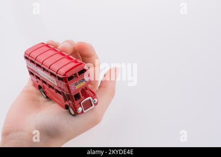 Hand hält einen London-Doppeldecker-Bus auf einem weißen Hintergrund Stockfoto