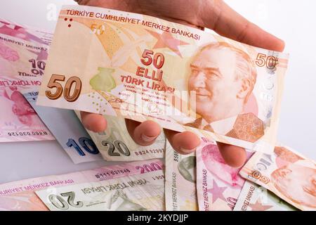 Hand mit Turksh Lira-Banknote auf weißem Hintergrund Stockfoto