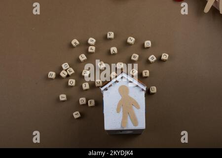 Hölzerne Buchstabenwürfel und Mannfigur und Modellhaus Stockfoto