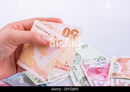 Hand mit Turksh Lira-Banknote auf weißem Hintergrund Stockfoto