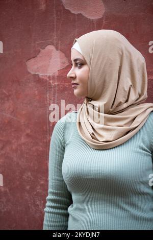Eine wunderschöne, nachdenkliche, muslimische Frau, die draußen wegschaut Stockfoto
