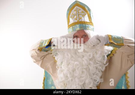 Sinterklaas porträtiert USA auf weißem Hintergrund. Holländischer Weihnachtsmann St. Nikolaus weihnachten Neujahr weißer Bart und goldblauer Anzug von St. Nikolaus auf weißem Hintergrund in der Studiowerbung Stockfoto